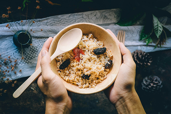 Hands holding a bowl of brown rice