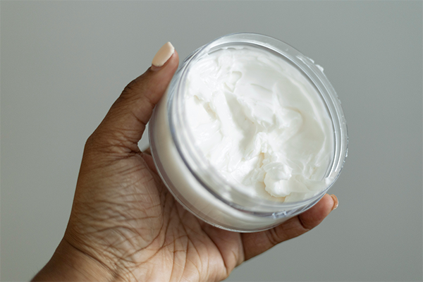Pot of cream in hand on white background