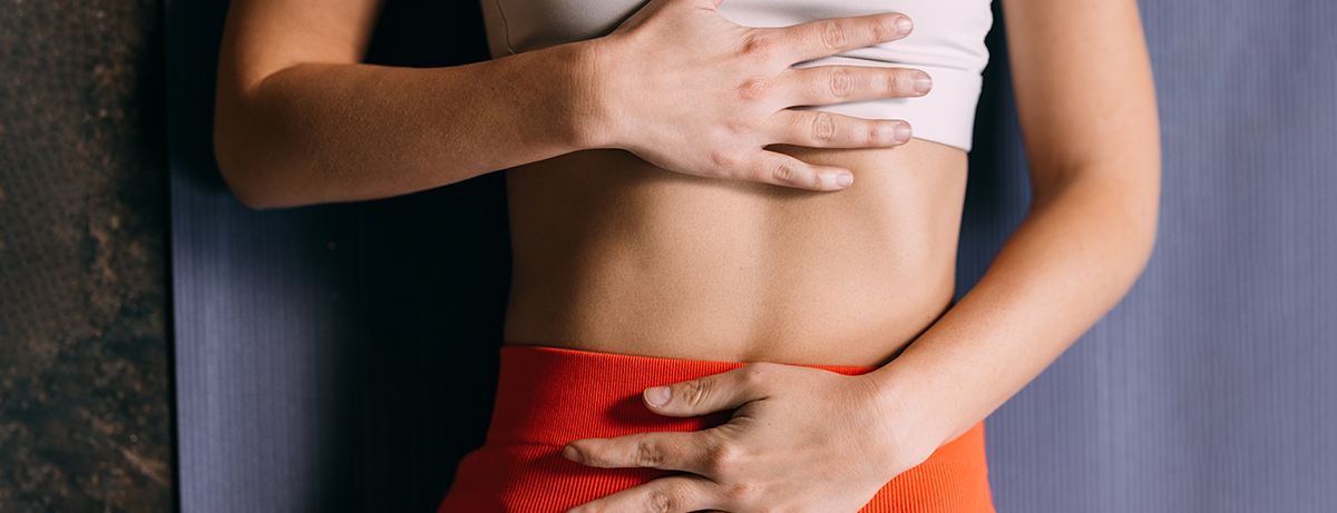 Female laying on yoga mat with hands on waist