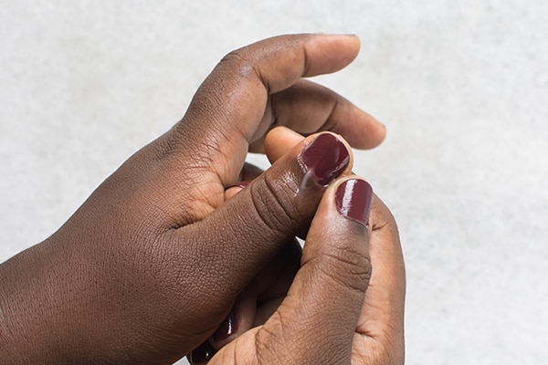 hand cream being applied on manicured nails, cuticle cream on brown skin hand