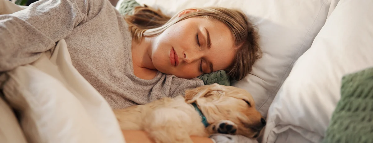 Female asleep with dog on the bed