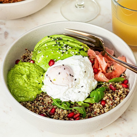 Quinoa healthy bowl with avocado, poached egg, pink ginger, green dresing and pomegranate with orange juice.