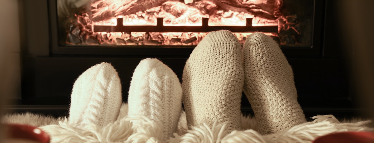 Couple in knitted socks near fireplace at home, closeup