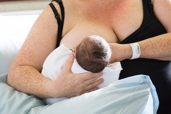 New mother feeding newborn baby in hospital using the football hold.