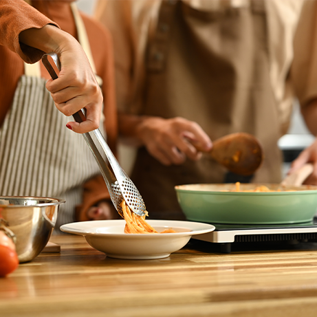 Young couple cooking spaghetti in a cozy kitchen. People, food and domestic life concept