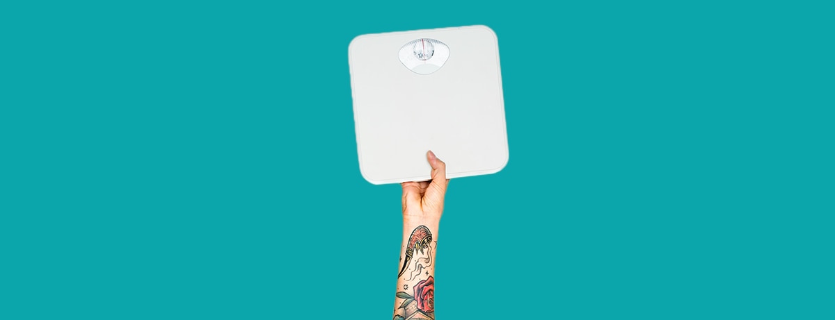 Hand holding up a weighing scales on blue background