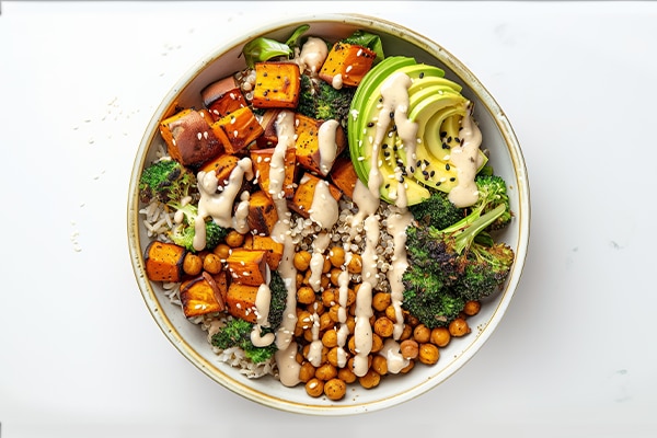 Vegan Buddha Bowl. A hearty bowl with a base of brown rice or quinoa, topped with roasted sweet potatoes, chickpeas, steamed broccoli, avocado, and a drizzle of tahini sauce