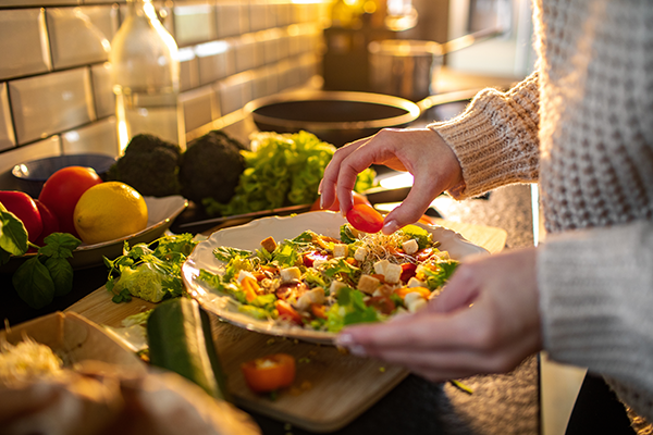 Young adult woman preparing a healthy salad in the kitchen