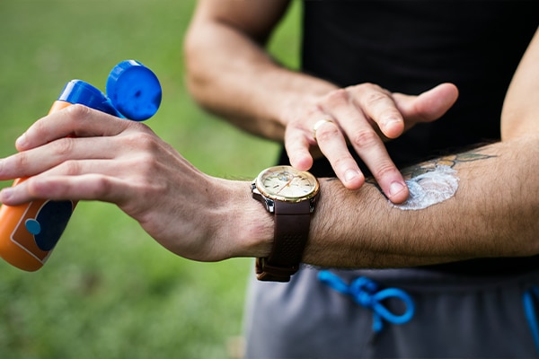 Close up of male applying spf on his arm