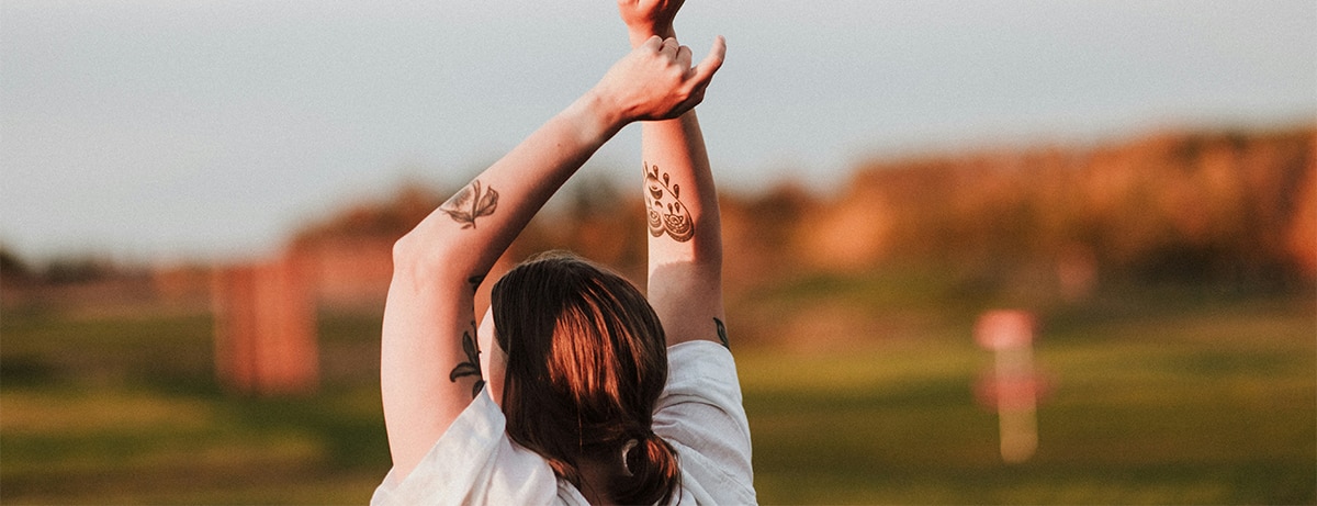 Female in the field holding arms in air