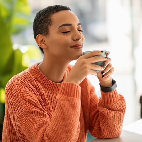 Glad calm pretty young latin woman enjoy peace and spare time, drink cup of coffee, warm moment in modern cafe, office interior. Rest, relax, ad and offer, human emotions, lifestyle