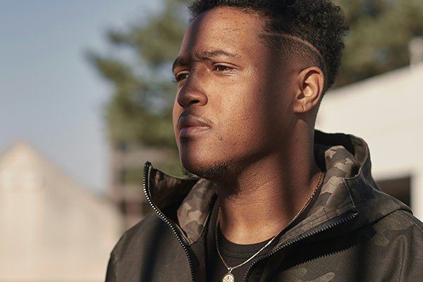 Male standing outdoors with calm expression