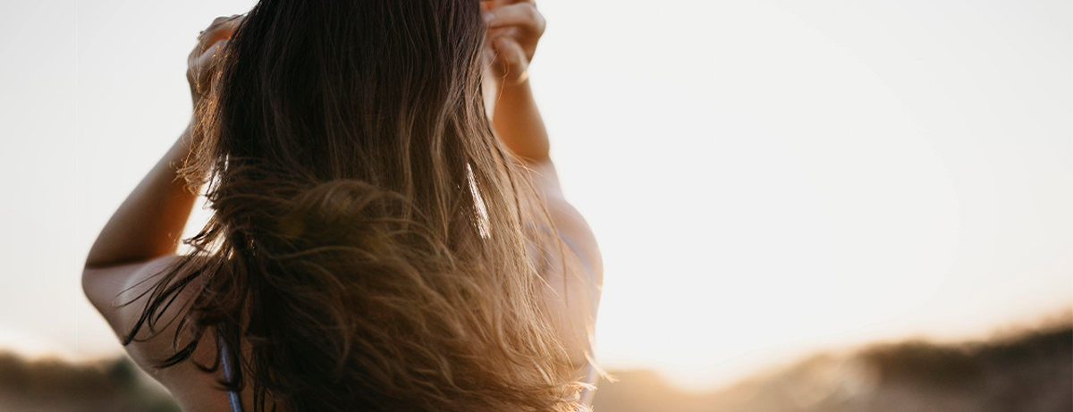 Female with back towards the camera, hands in hair
