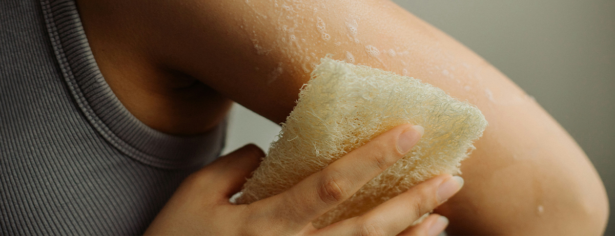 female scrubbing her skin with a sponge