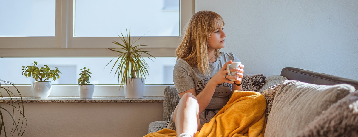 Female sitting on the sofa holding mug of tea