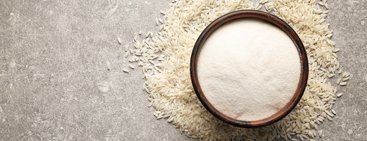 Bowl with rice flour on gray background