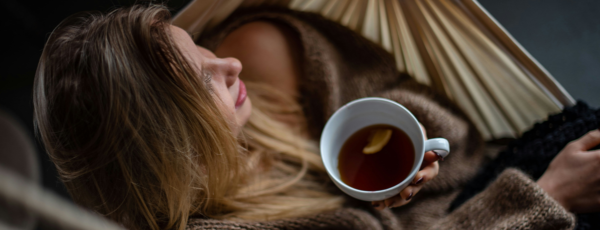 Female resting in bed with a herbal tea