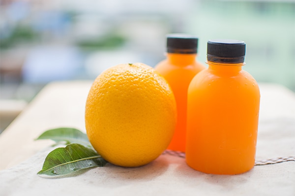 orange and orange juice with leaf on wooden table at sunny day. soft focus.