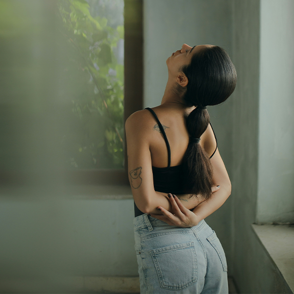 Female standing in home stretching. Calm expression