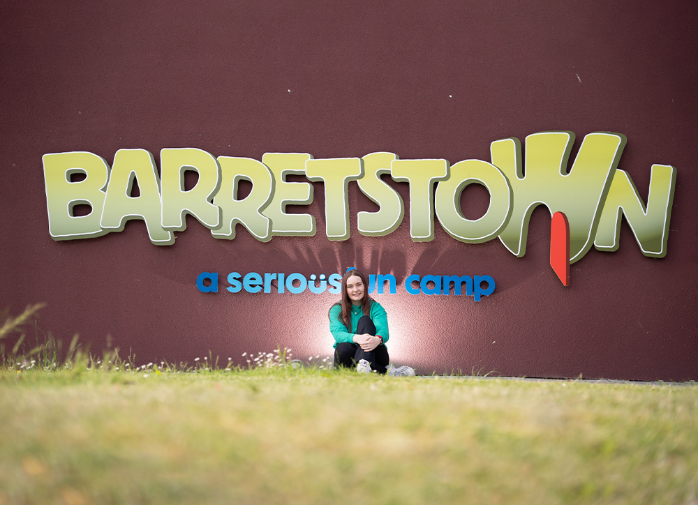 Female standing underneath a barretstown sign
