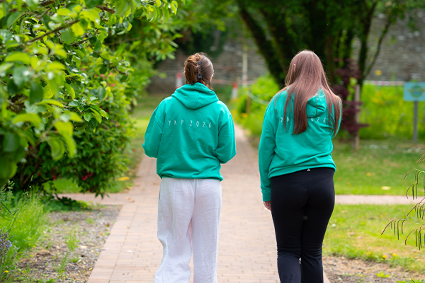 2 females walking in the park looking away from the camera