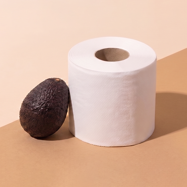 Toilet roll and avocado on beige background