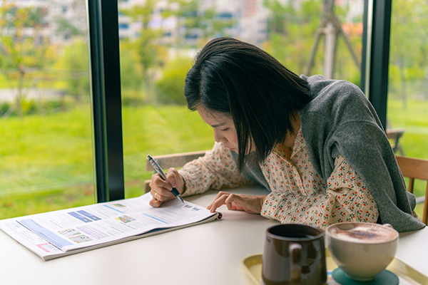 Female sitting in front of window sketching on paper