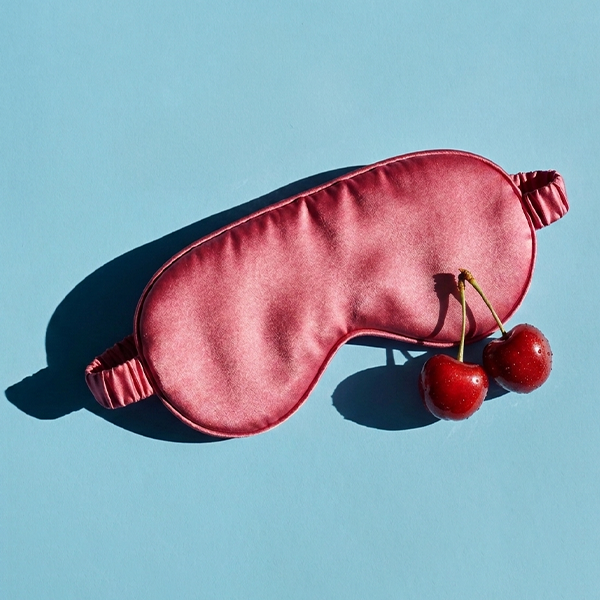 Eye mask and cherries on a blue background