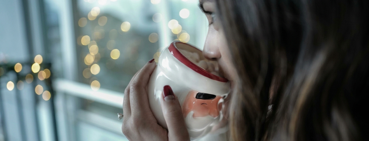 Female drinking hot chocolate in front of window