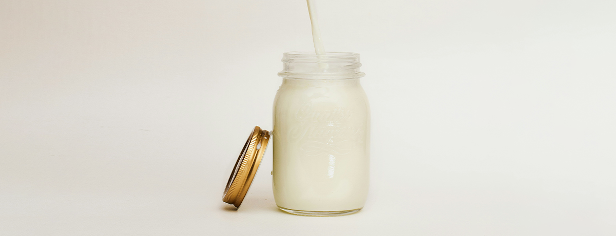 milk being poured into glass on white background