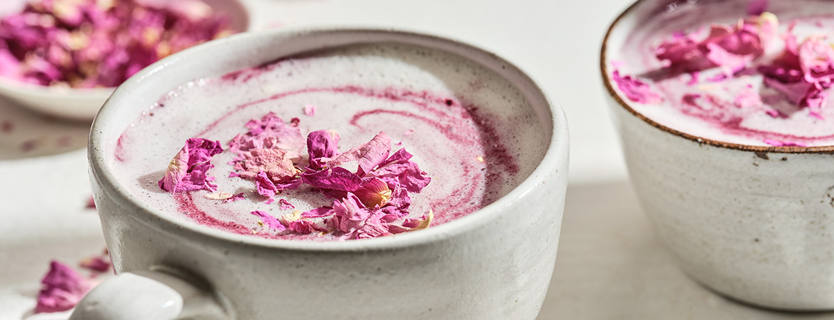 A mug of pink strawberry tea with flower petals