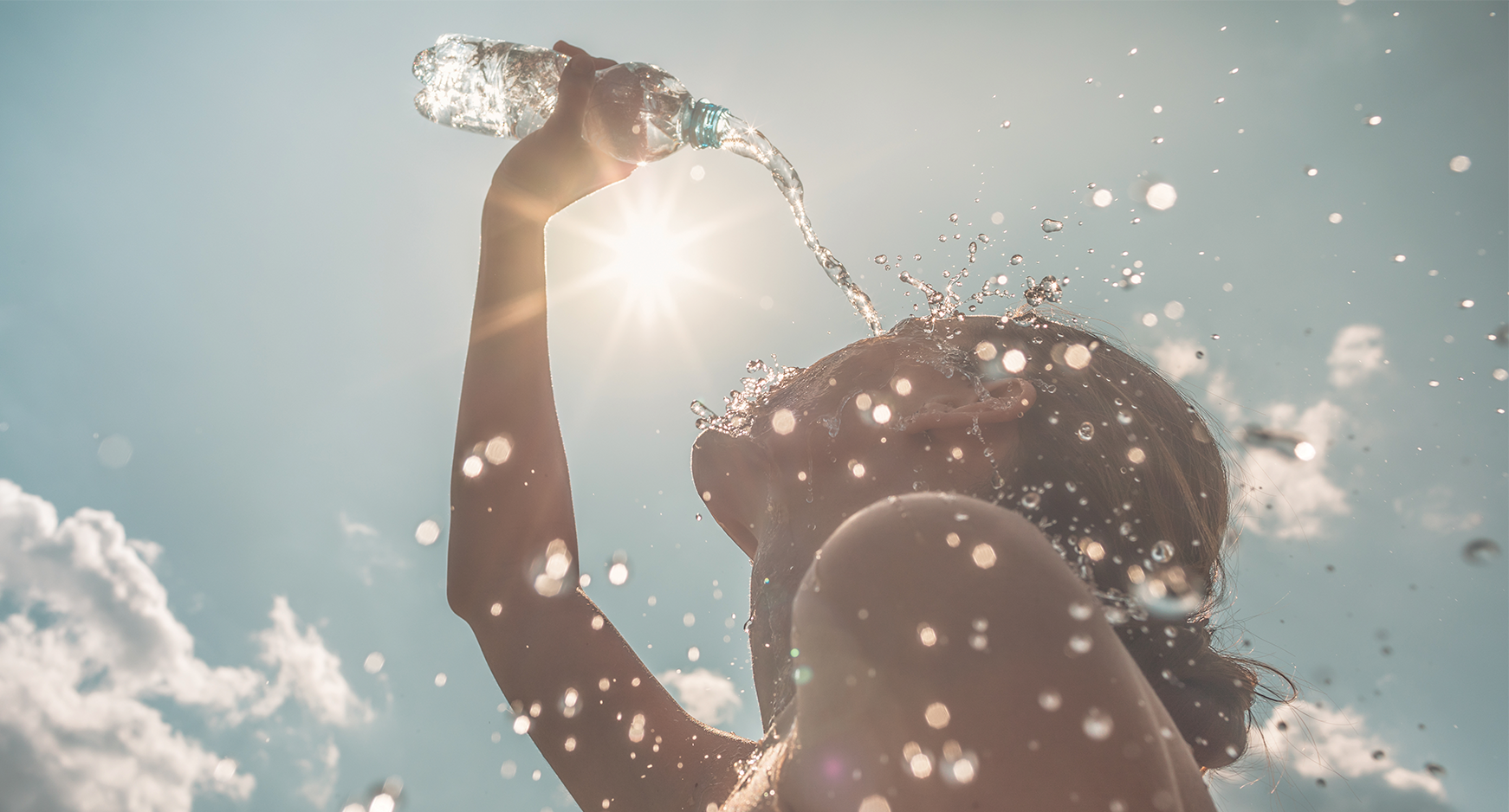 female pouring bottle of water over herself