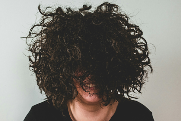 Female with curly hair covering face