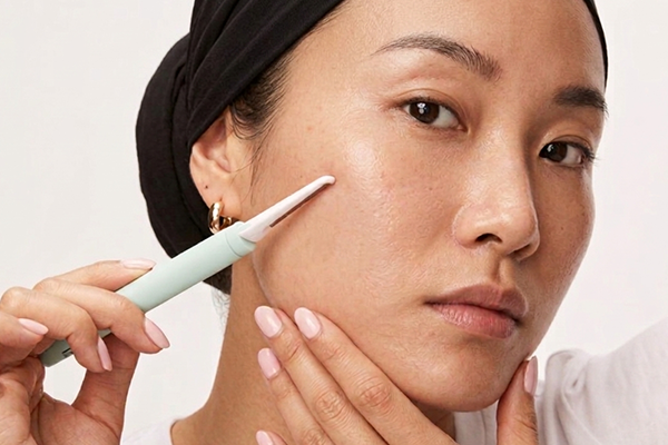Female holding dermaplane pen to face, close up