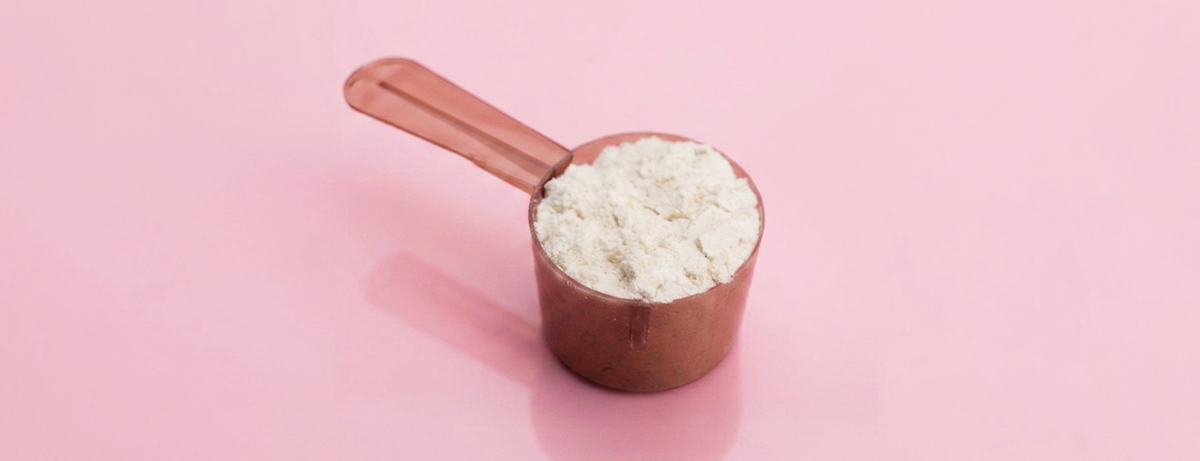 Dextrose sugar in a scoop on a pink background
