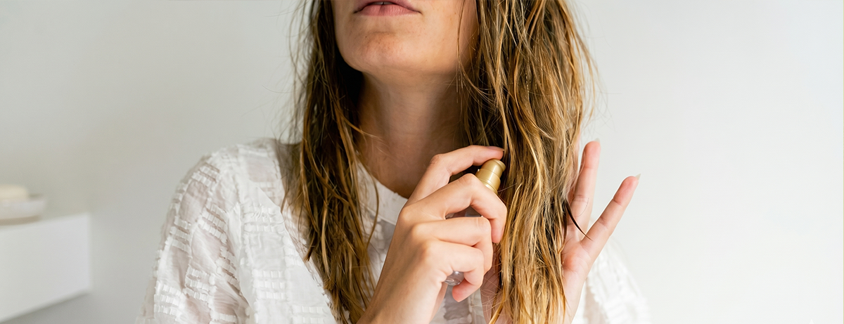 Female applying oil to hair