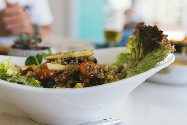 Healthy meal in a white bowl, blurred hands in the background