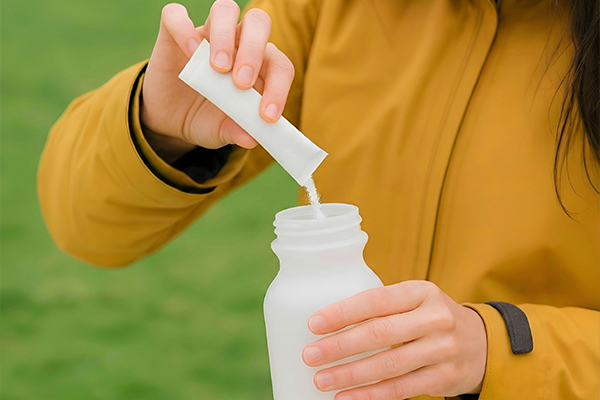 Female pouring electrolyte powder into sports bottle