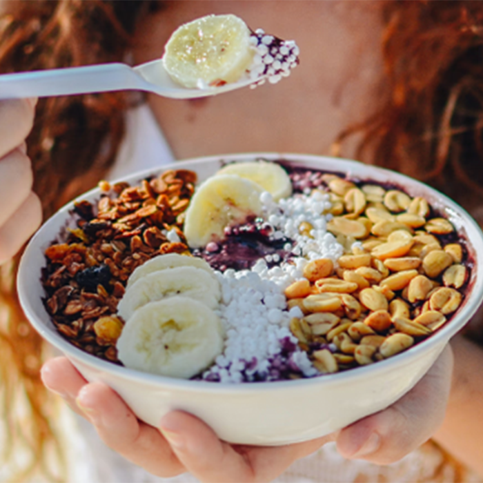 Hand holding a bowl of granola and banana
