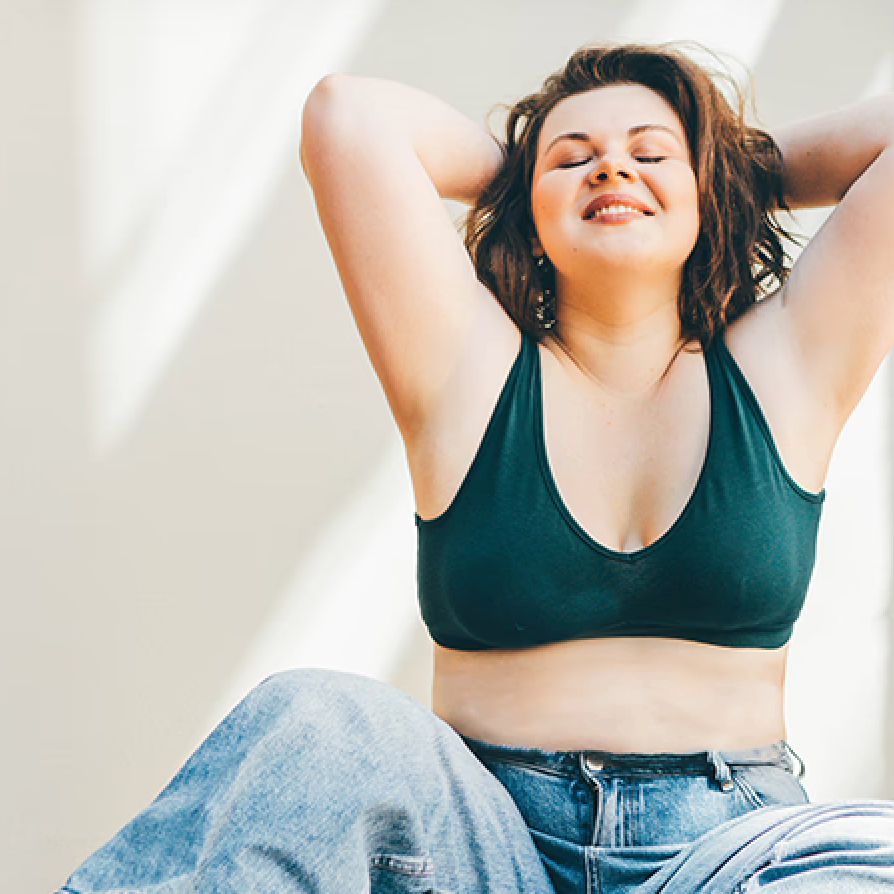 Female sitting with happy expression against a wall