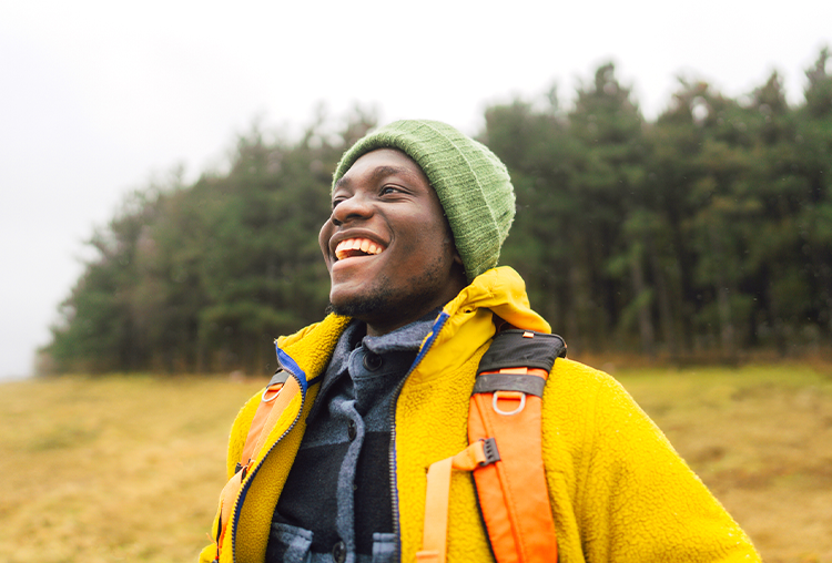 Male in yellow coat outside smiling away from the camera