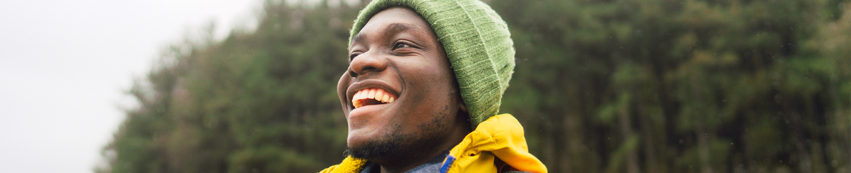 Male in yellow coat outside smiling away from the camera