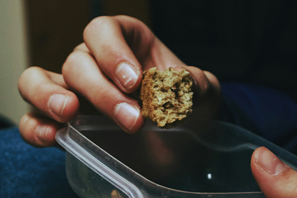Hand holding protein bar on top of plastic tub