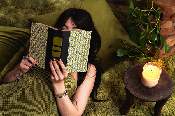 female reading a book at home with a candle