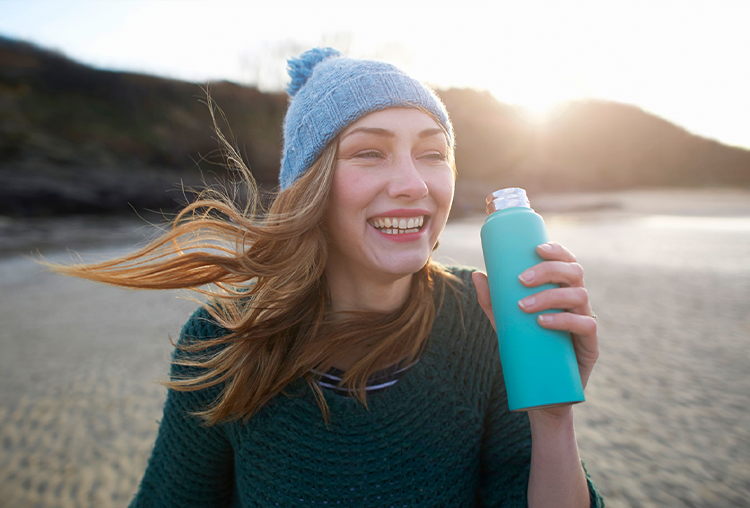 Female with water bottle and winter hat standing outside