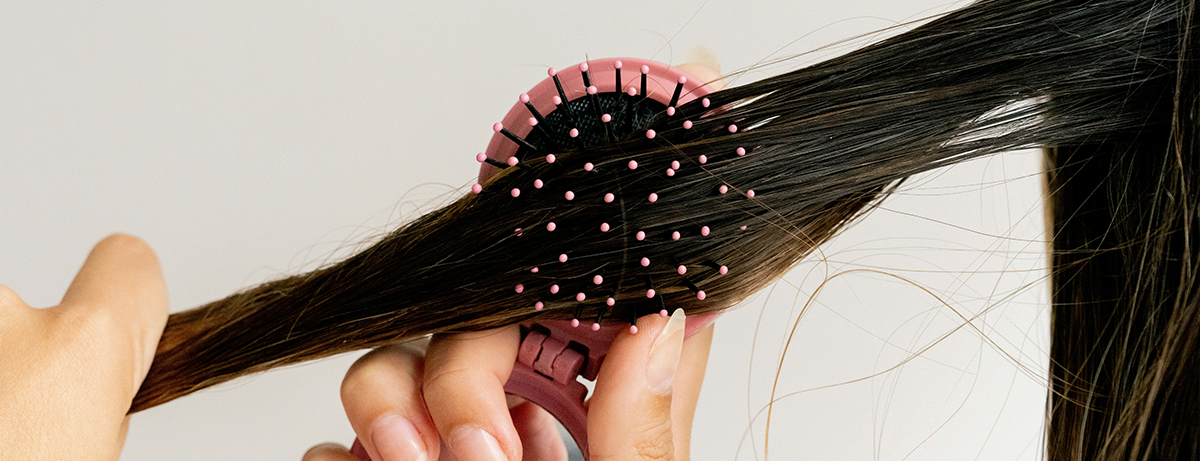 Female brushing hair, close up of hair and pink brush