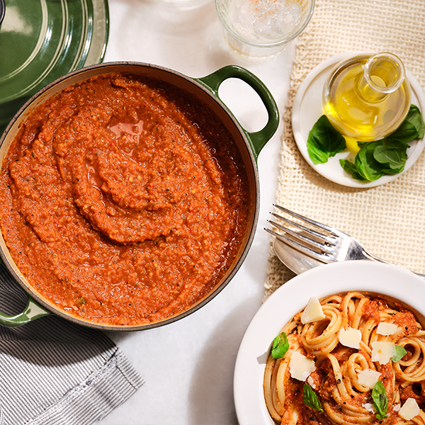 bowl of red lentil soup next to some pasta, on kitchen worktop