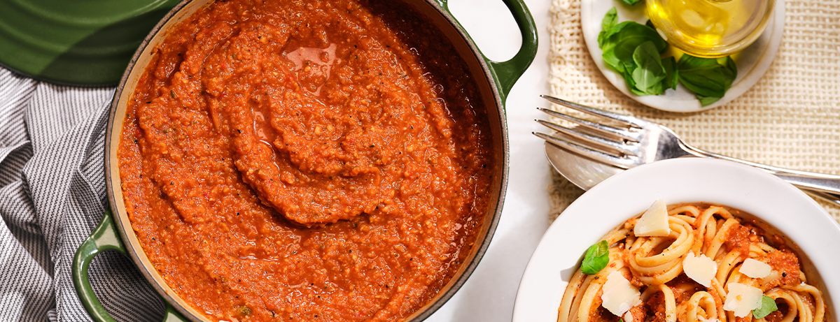 bowl of red lentil soup next to some pasta, on kitchen worktop