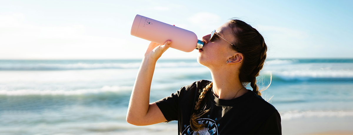 female on the beach drinking water