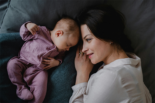 Female asleep on bed with baby